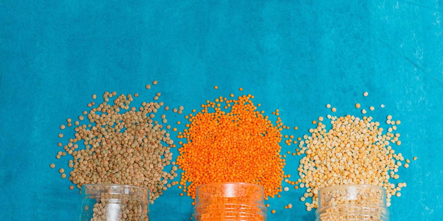 Spilled lentils in jars on a blue plaster background. high angle view.